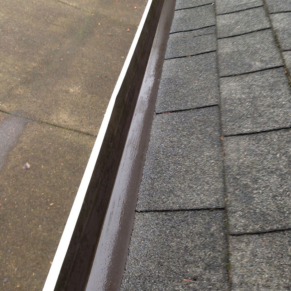 Wet metal railing at a diagonal angle on a paved sidewalk, indicative of recent rain.